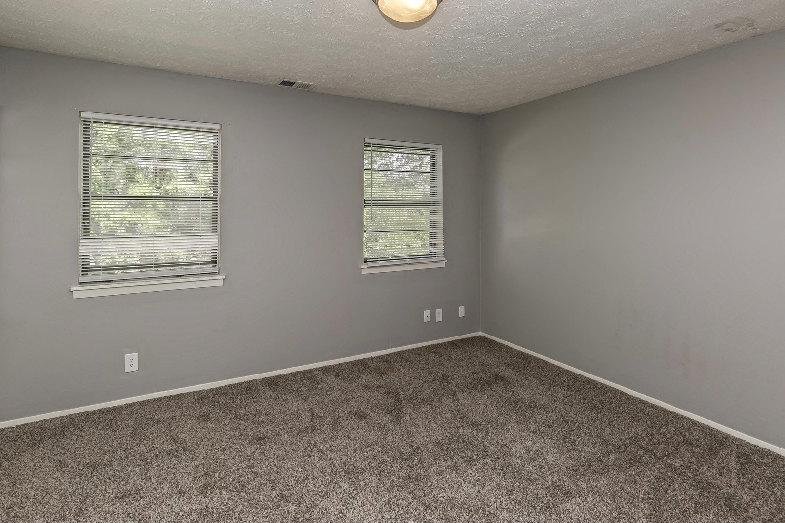Large carpeted bedroom with window coverings at Terrace Garden Townhomes